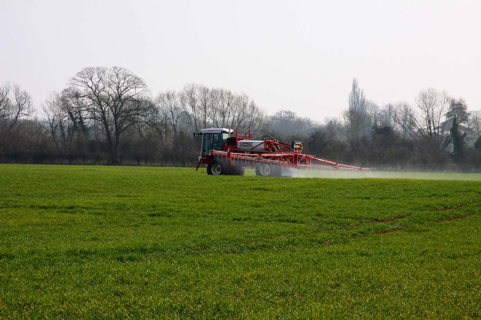 A boom sprayer working across an open field.