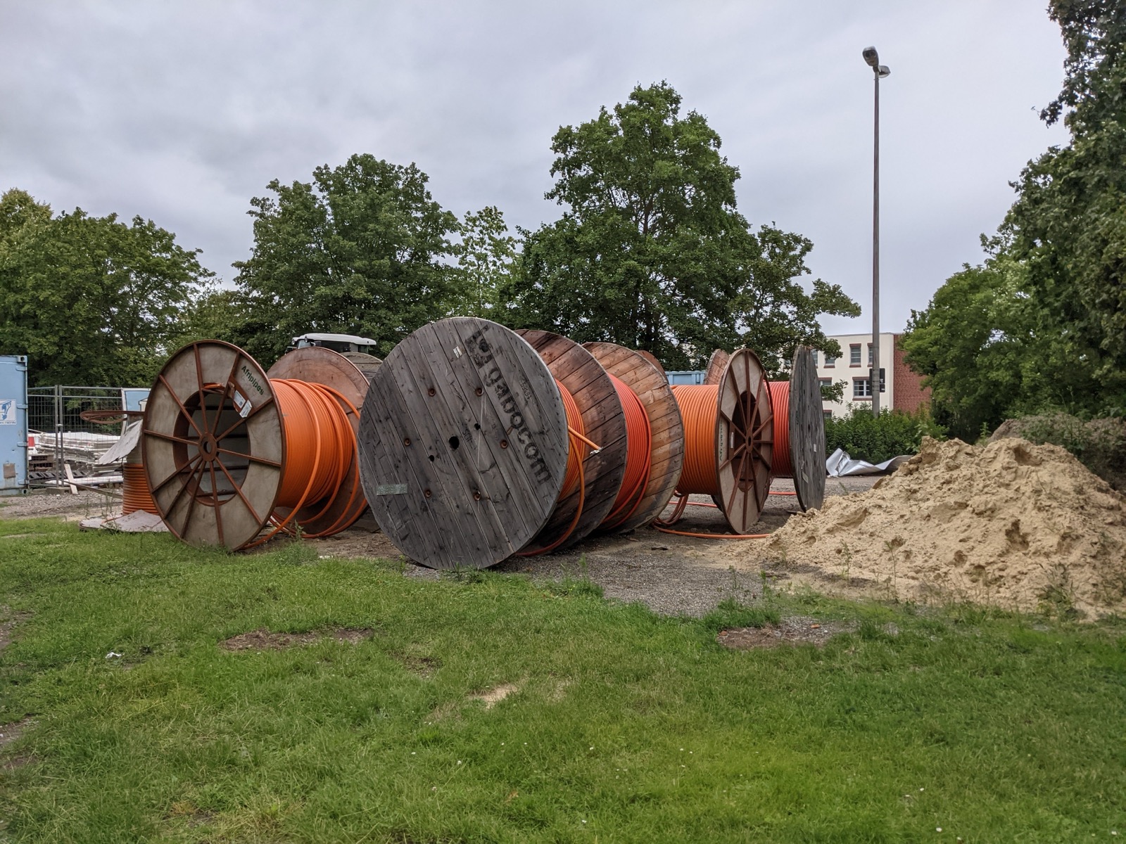 Cable drums of orange fibre conduit standing at a street works site.