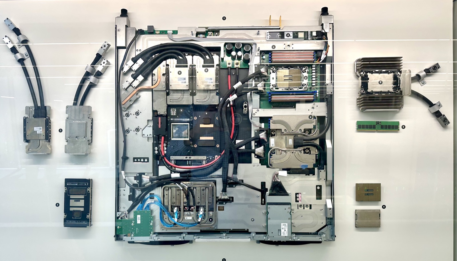 A liquid-cooled GPU blade laid out beside the cold plates, processors and memory it is assembled from.